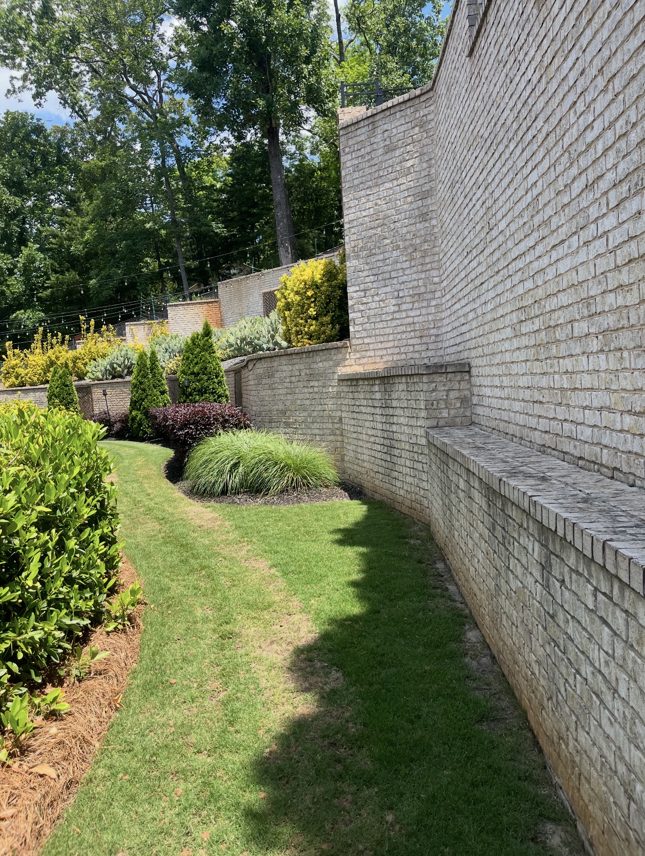 White brick retaining wall with tiered landscaping