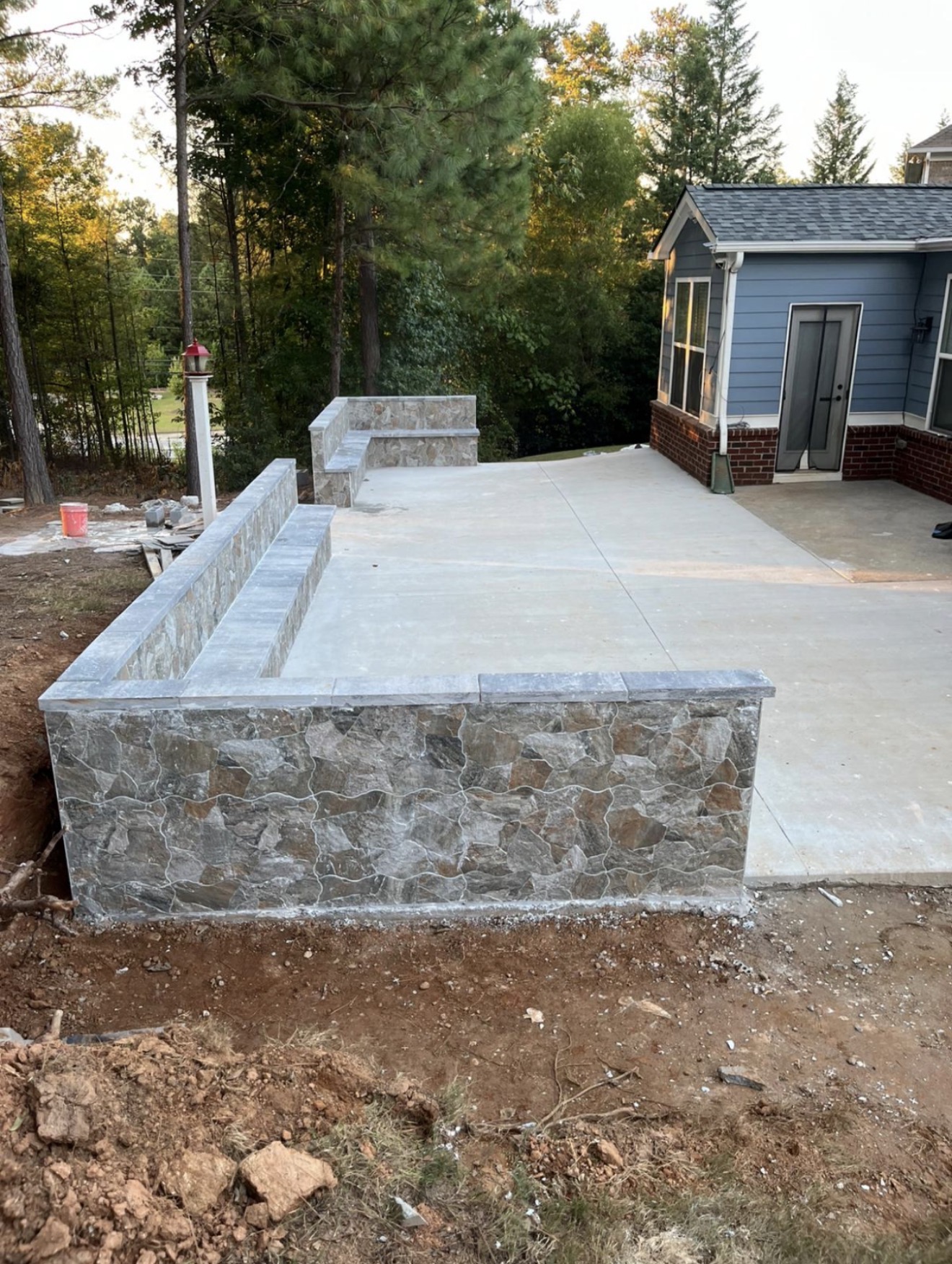 Custom stone veneer wall and concrete patio by Legacy Construction